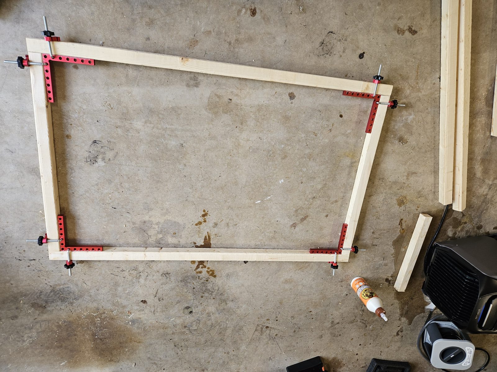 The 46 by 29 inch Panel A frame glued and held square with four right-angle corner clamps on a garage floor
