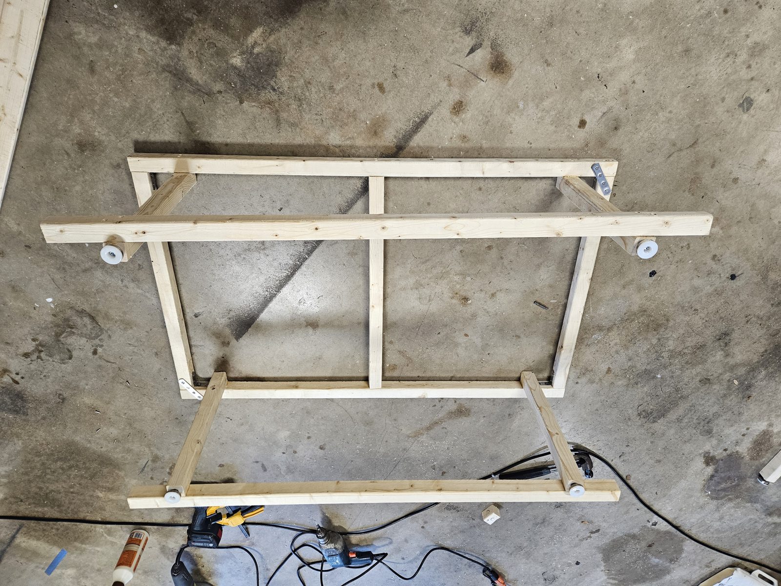 The completed Panel A frame standing inverted, showing four legs with leveling feet, the centre divider, bottom rails and metal straps at two corners